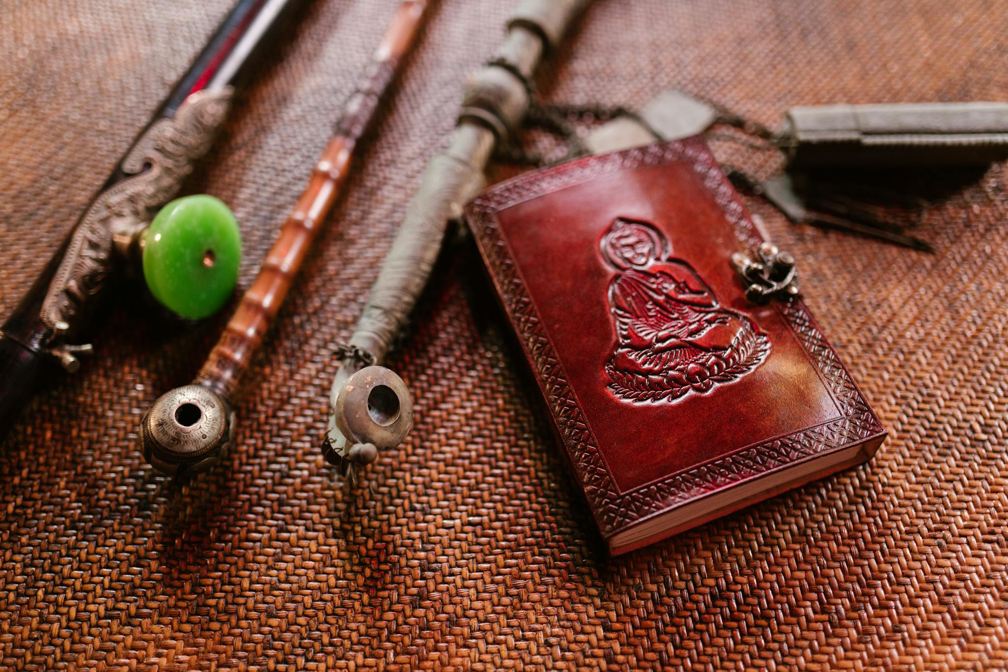 A collection of vintage Buddhist artifacts including a leather book and pipes on a textured surface.